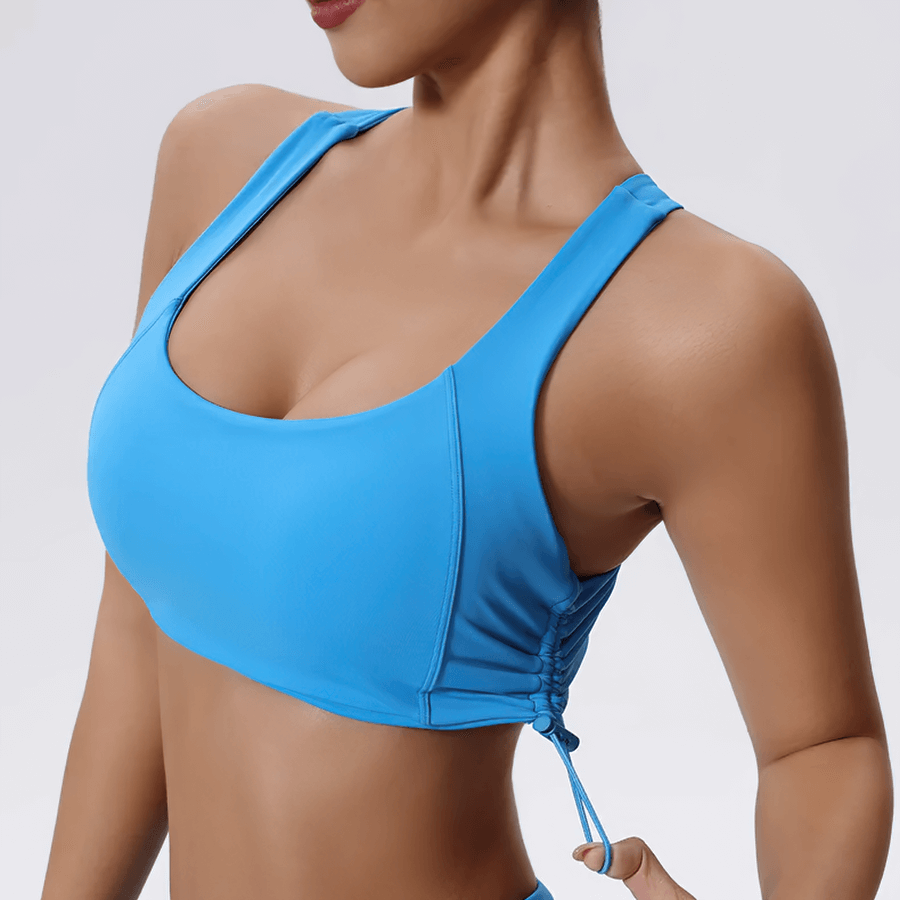Woman wearing blue sexy adjustable sports bra for fitness and yoga with drawstring sides, ideal for high-impact workouts.